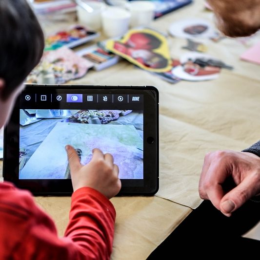 Ein Kind zeigt einem Erwachsenen etwas auf dem Tablet