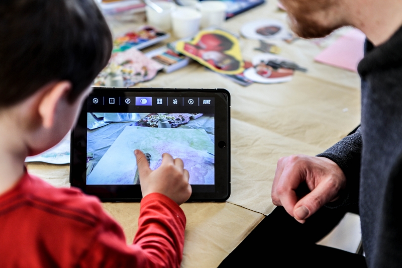 Ein Kind zeigt einem Erwachsenen etwas auf dem Tablet