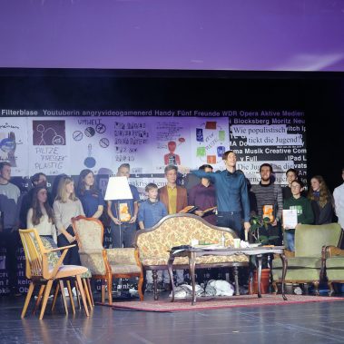 Gruppenfoto der Preisträger:innen auf der großen Bühne