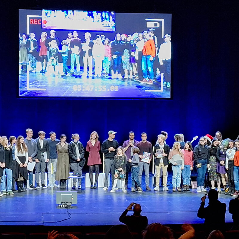Auf einer Bühne stehen die Gewinner und Gewinnerinnen im Rampenlicht.