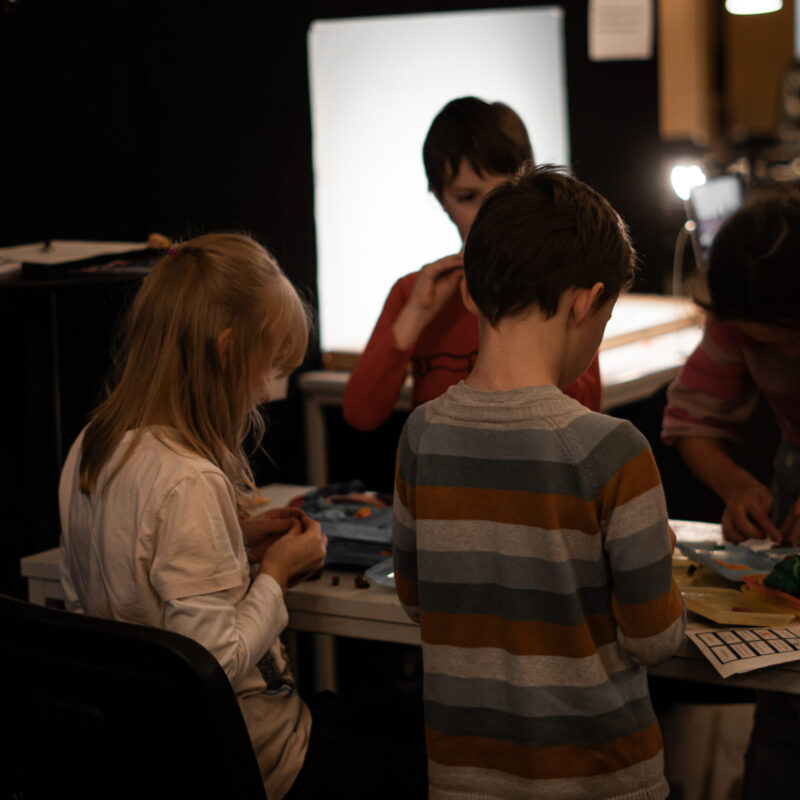 Drei Kinder stehen an einem Tisch und basteln Knetfiguren.